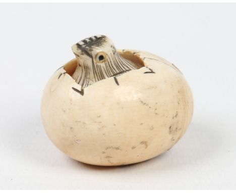 A Japanese carved ivory netsuke. Formed as a chick hatching from an egg, the chick is carved separately and sits loosely with