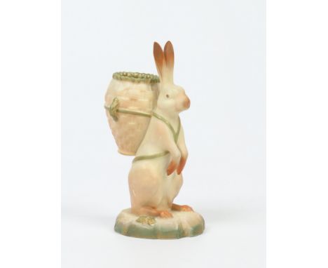 A Royal Worcester blush ware novelty match holder. Formed as a rabbit holding a basket upon its back and raised on a naturali