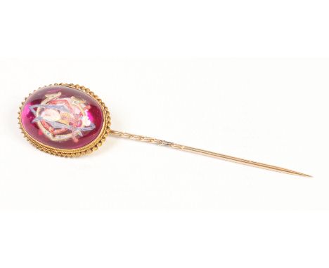 A Victorian gilt metal tie pin with a large ovoid crystal terminal. Claret ground with foil back and carved and enamelled wit