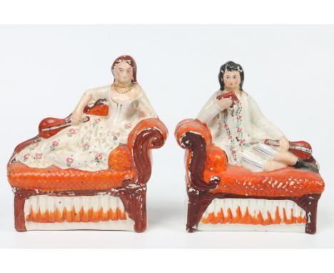 Two Victorian Staffordshire figures. Formed as a lady and gent, each reclining on a scroll arm settee, 19cm wide. Condition R