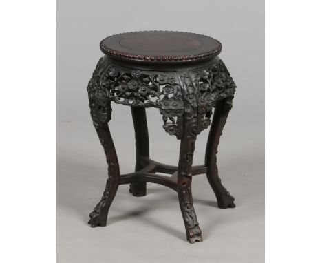 A 19th century Chinese carved hardwood jardiniere stand profusely carved with flower heads and raised on scroll supports, 49c