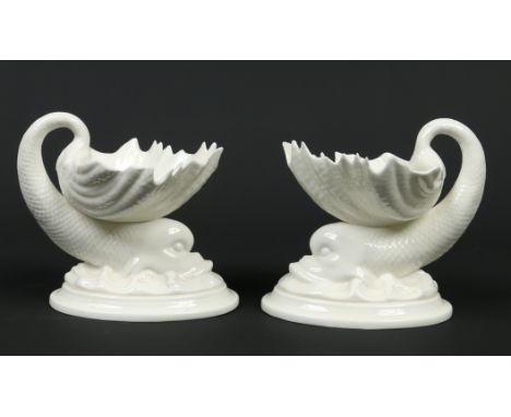 A pair of Royal Worcester white glazed pedestal salt cellars. Each formed as a shell supported by a dolphin. Printed green ma