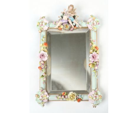 An early 20th century Dresden mirror with bevelled glass. Ornamented with a pair of putti and having applied fruit and flower