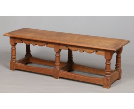 An early 20th century Georgian style light oak coffee table raised on turned supports and with cross stretchers, 142cm.