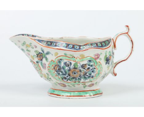 A large Worcester strap moulded sauceboat. Painted in underglaze blue with flowers and having clobbered decoration in red and