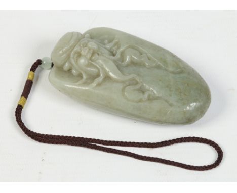 A Chinese carved celadon jade pendant with very slight russet suffusions and in the form of a bearded lohan, 9cm. Condition R