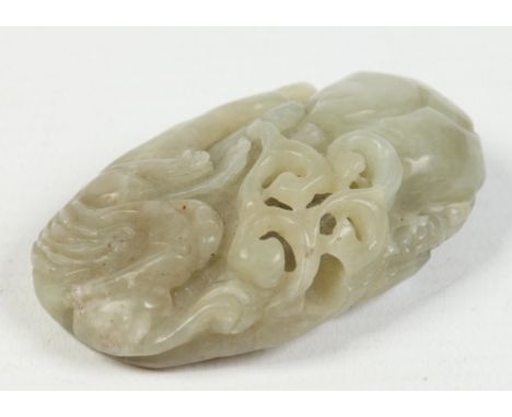 A Chinese celadon jade pendant. Carved in the form of a Kylin with an openwork ruyi branch and and a peach, 6.75cm. Condition