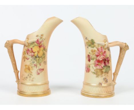 A pair of Royal Worcester blush ground tusk jugs with moulded stag antler handles. Edged in gilt and decorated with flowers. 