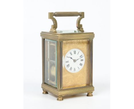 A late 19th century French brass cased carriage clock with scroll engraved gilt mask and enamel dial having Roman numeral mar