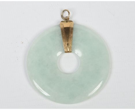 A celadon jade pendant of compressed disc form and with yellow metal mount, 5.25cm diameter. Condition Report. To be used as 