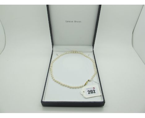 A Modern Single Strand Pearl Bead Necklace, the uniform beads knotted to textured clasp, stamped "375". 