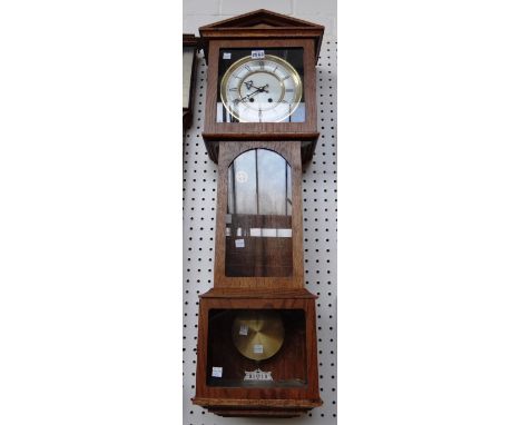 A wall clock with regulated escapement, white enamel dial in an oak case with architectural hood. 

Provenance:  Bramshill Ho