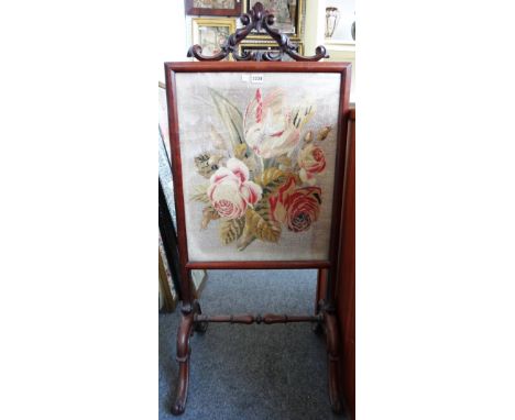 A Victorian rosewood fire screen with scroll crest and foliate wool work panel over cabriole legs united by a central stretch