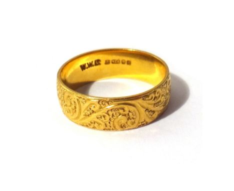 A 22ct gold wide band wedding ring, with scroll engraved decoration, London 1975, ring size N, weight 5 gms.