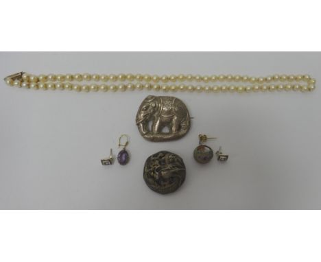 A single row necklace of uniform cultured pearls, on a hexagonal clasp, an Oriental brooch, designed as an elephant, a large 
