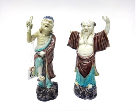 A pair of Chinese porcelain figures of Immortals, 19th century, each standing on  a scroll moulded base, one with a crutch an