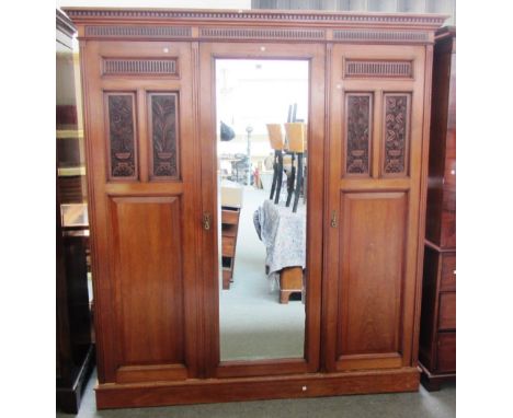 A late 19th century walnut compactum wardrobe with mirrored central door bearing an enamel plaque for 'James Shoolbred & Co',