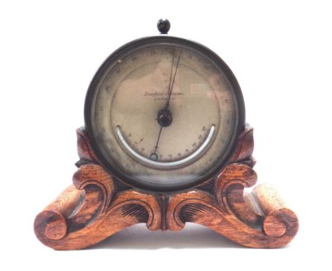 A Victorian brass cased table barometer by 'Troughton and Simms, London', with inset thermometer, 12cm diameter, on a carved 