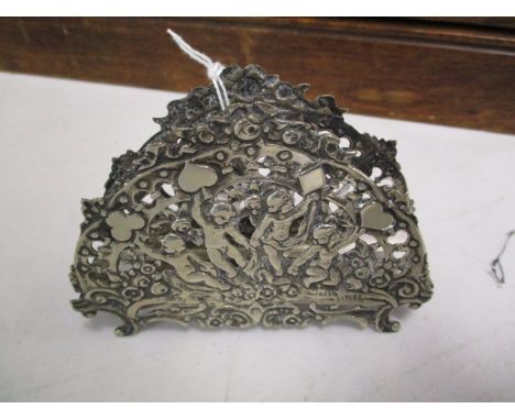 A silver playing cards holder decorated with children and the four suits