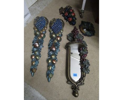 A group of painted cast metal and plaster wall mirrors and plaques in the form of grapes, fruit and leaves, along with two gi