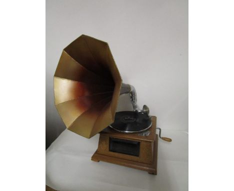 A light oak cased gramophone with a glazed front, flanked by carved leaves, with a horn, and a Bing Crosby record