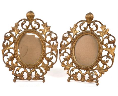 A PAIR OF LATE 19TH C GILT IRON PHOTOGRAPH FRAMES, THE OVAL APERTURE IN SCROLLING FOLIATE SURROUND, HINGED STRUT, 28CM H 