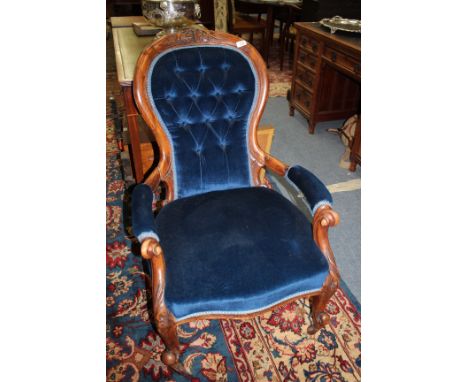 A VICTORIAN WALNUT OPEN ARMCHAIR with carved cresting rail to the shaped button upholstered back, with overstuffed upholstere