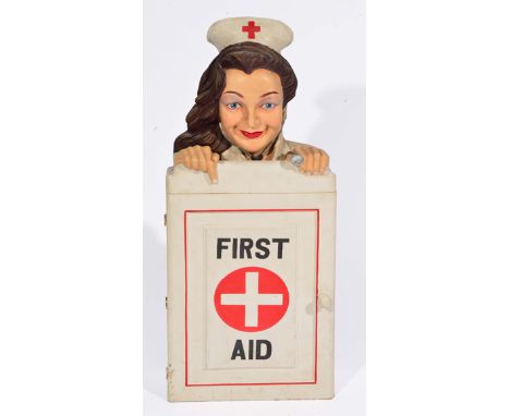 A PAINTED WALL HANGING FIRST AID CABINET with a head and shoulders of a nurse peering over the top, 35cm wide x 56cm high 