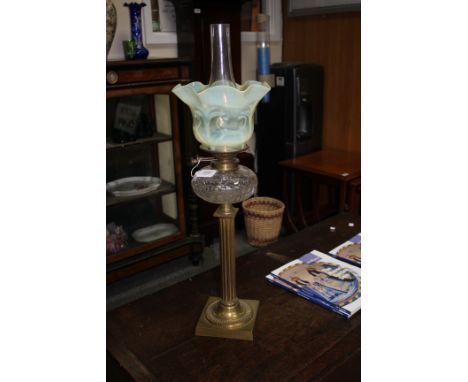 A VICTORIAN BRASS OIL LAMP with opaline shade and standing on pilaster column supports with square spreading base  