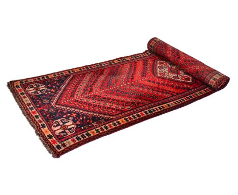 AN ORIENTAL RED GROUND RUNNER with central diamond motif, flanked by bands of geometric designs within a triple banded border