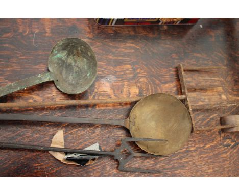 AN ANTIQUE WROUGHT IRON TOASTING FORK with four tines, 77cm long together with a further toasting fork and two ladles (4)