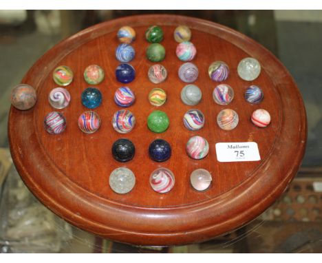 A TURNED MAHOGANY BAGATELLE BOARD complete with a selection of various 19th century and later marbles, 30cm diameter