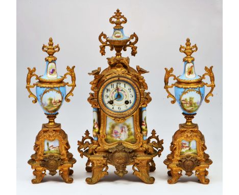 A FRENCH GILT METAL PORCELAIN MOUNTED GARNITURE DE CHEMINEE topped with urn finial, the case decorated with scrolls and birds