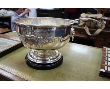 A SILVER PLATED PUNCH BOWL with two scroll and foliate cartouches, lion head and ring handles standing on a turned stepped fo