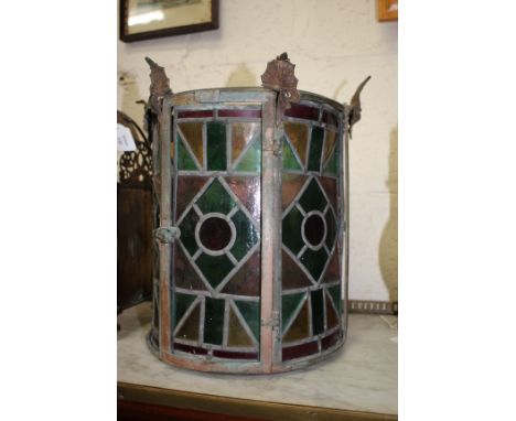 AN OLD BRASS CYLINDRICAL HALL LANTERN with cast finials and inset with leaded glass panels 26cm diameter x 35cm high