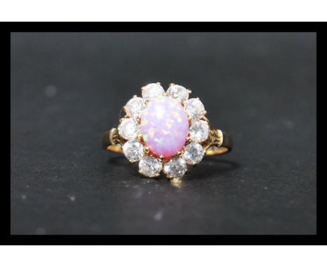 A 14ct gold cluster ring set wit a central pink opal style stone surrounded by a halo of white stones.&nbsp; Marked 585, test