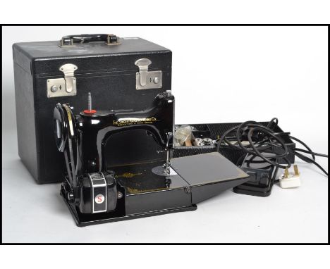 A vintage 20th century Singer Featherlite sewing machine being complete in the original carry case with handle atop.
