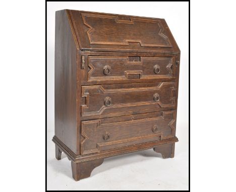 A 1920's Jacobean oak bureau desk raised on bracket legs with geometric panelled drawers under bureau atop