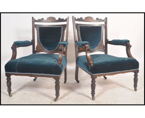 A pair of Edwardian mahogany and seaweed inlaid ladies and gentlemans salon armchairs. Each raised on turned legs with cerami