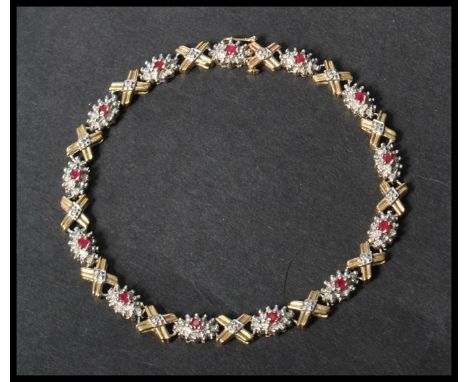 A hallmarked 9ct white and yellow gold ruby and diamond bracelet set with gold kiss and cluster settings . Set with 13 round 