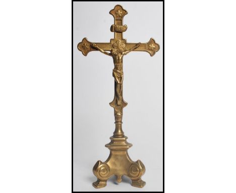 An Early 20th century brass Ecclesiastical Crucifix. The cross raised on a scrolled tripod base. Measures 33.5 cm high.