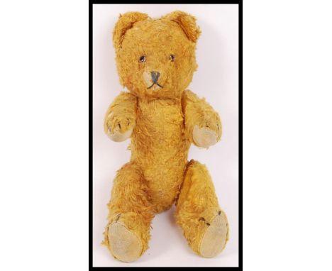 A vintage 1940's likely Chiltern golden wood wool stuffed small child's teddy bear, with glass eyes. Measures approx 24cm tal