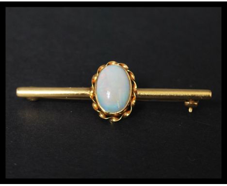 A hallmarked 9ct gold and opal brooch pin set with a single opal cabochon in a twist setting having a roller clip clasp. Weig