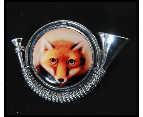 A sterling silver hunting brooch in the formof a hunting hron with enamel pictorial of a fox. Weighs 14 grams measures 4cms w