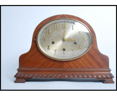 An early 20th century Napoleons hat mantle clock having a carved base with domed top. The silvered dial having gilt faceted h
