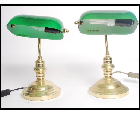 A matching pair of vintage 20th century brass bankers lamps raised on circular bases with adjustable green shades.