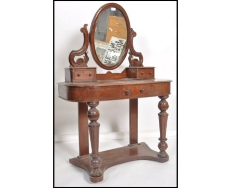 A Victorian mahogany duchess dressing table raised on turned legs with trinket drawers below swing mirror, the base with shap