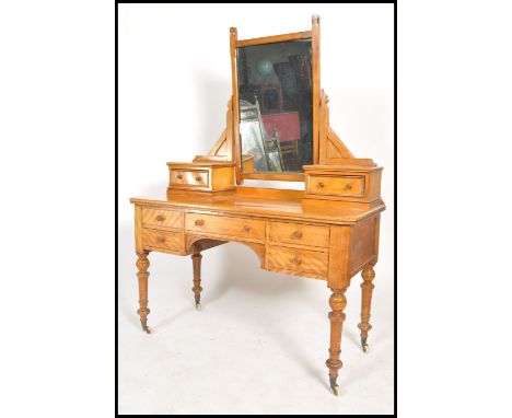 A Victorian 19th century satin birch wood duchess dressing table being raised on turned legs with castors. Above a fitted fri