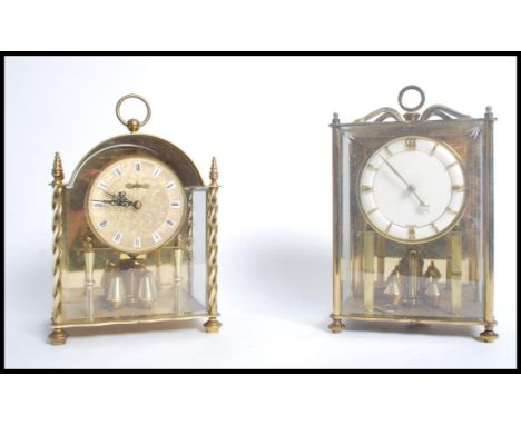 Two vintage 20th century brass and glass panelled anniversary clocks. One by Koma with gilt face Roman numerals and faceted h