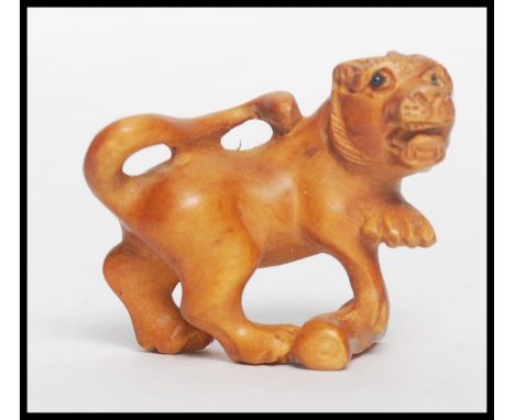 A Chinese carved netsuke in the form of a temple lion dog of Fu with signature to underside. Measures 4.5cms high.